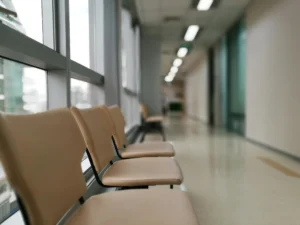 An empty waiting room with rows of chairs, a reception desk in the background, symbolizing the financial and operational impact of missed medical appointments or 'ghosting' by patients in healthcare practices.