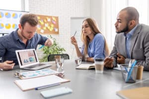 receptionist scheduling 3 people discussing chart in laptop