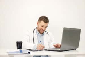what does a virtual medical scribe do man doctor writing in front of laptop