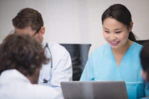 Nurse using laptop in clinic meeting for online reputation management for doctors and healthcare branding strategy.