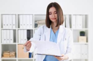 patient care coordinator duties Female healthcare professional in a white coat reviewing medical documents