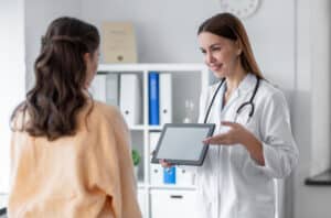 patient care coordinator duties Smiling female doctor showing medical information on a tablet