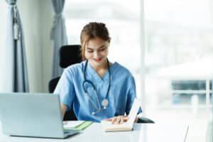 virtual assistant services for medical practice Smiling female medical professional working on a laptop