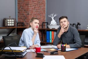 what does executive assistant do Two office colleagues sitting at a desk with documents and laptops