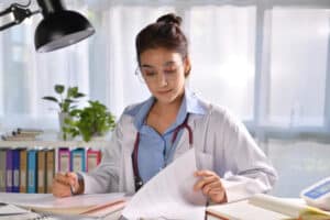 what is a scribe in healthcare Female doctor reviewing patient medical records and taking notes
