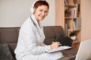 A doctor takes notes online, showcasing virtual healthcare assistant solutions