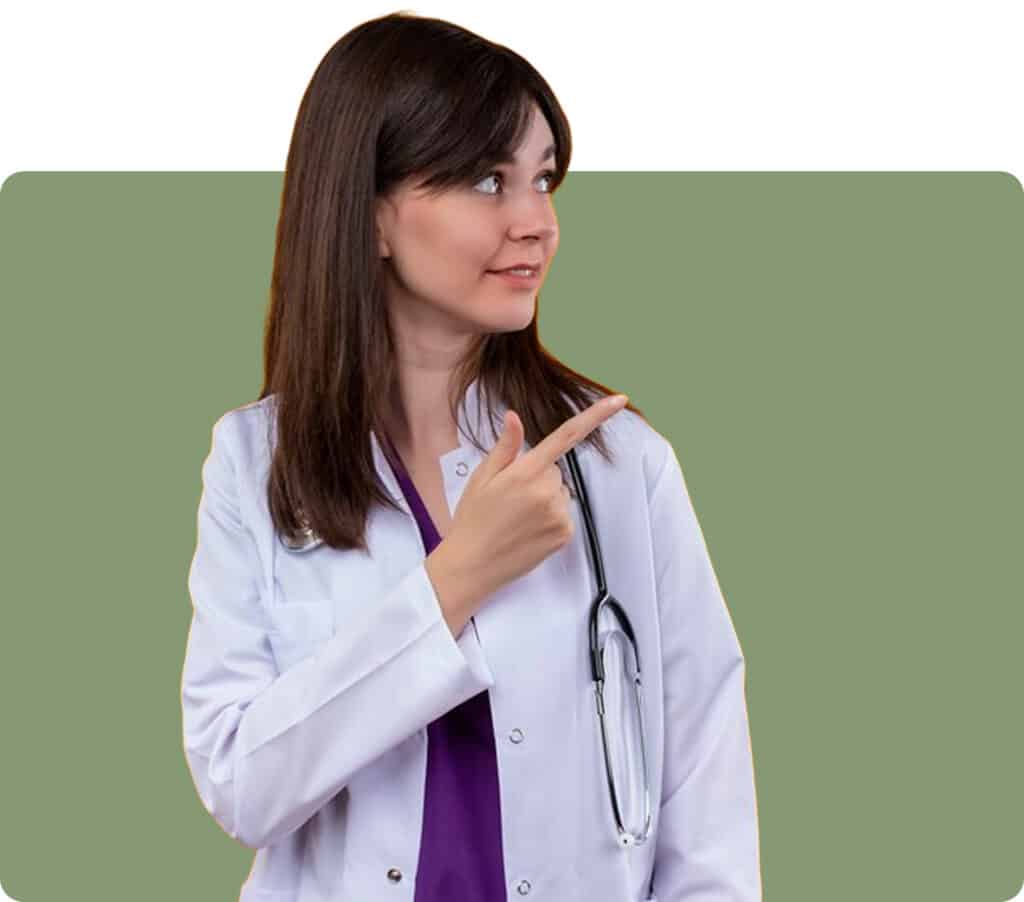 Female doctor in white coat with stethoscope smiling and pointing sideways on green background