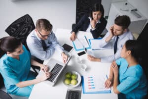 Medical and business professionals in a meeting reviewing charts and data