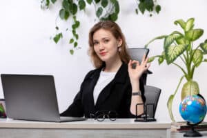 receptionist jobs near me Smiling female professional sitting at office desk with laptop