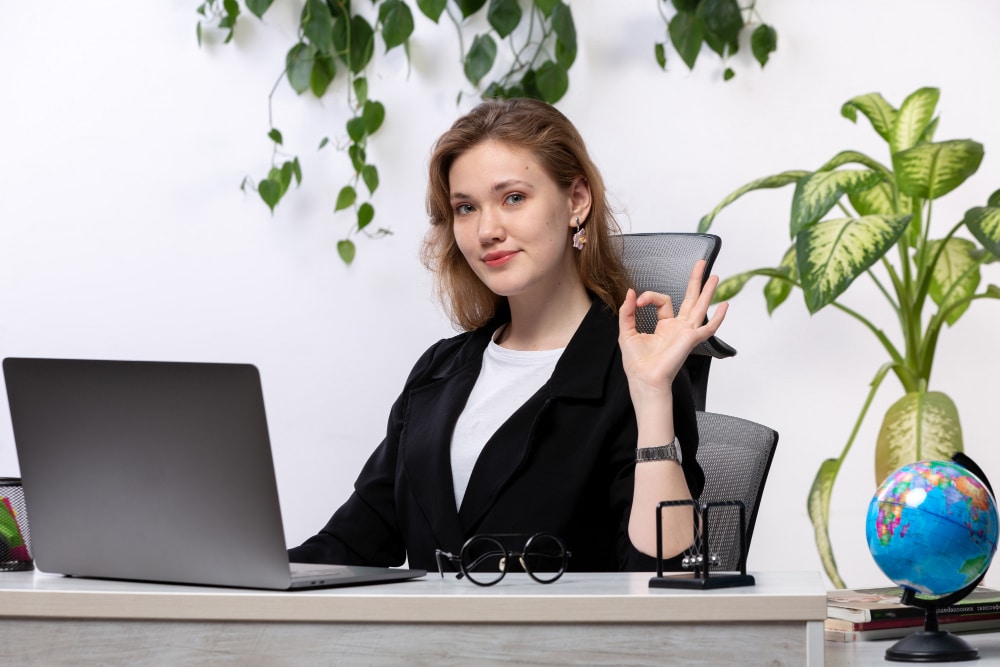 receptionist jobs near me Smiling female professional sitting at office desk with laptop