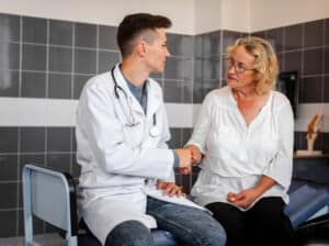 A doctor consults with a patient during an appointment, supported by a doctors scribe