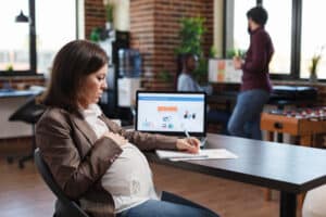 A pregnant woman works at a desk, symbolizing maternal health service billing