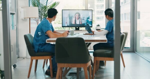 Medical team having virtual meeting with doctor via video conference in modern healthcare office