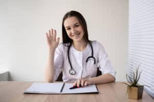 definition of receptionist Smiling female doctor greeting patient at desk with stethoscope