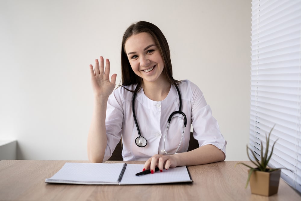 definition of receptionist Smiling female doctor greeting patient at desk with stethoscope