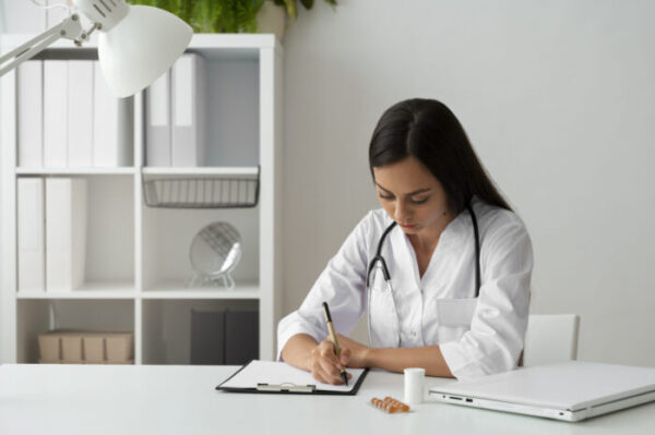 medical scribing by a focused physician writing on documents in a bright office