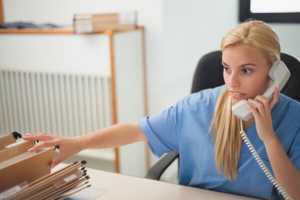 female nurse checking on records while taking calls