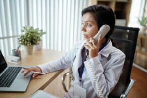 telephone triage escalation workflows for outpatient clinics doctor facing to her laptop while calling the patient