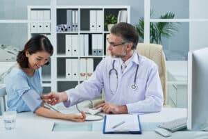 Doctor checking a female patient’s blood pressure during a post-discharge escalation workflow in a specialty clinic.