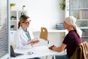 Doctor explaining at the clinic, patient journey ownership model for specialty clinics, during a consultation with a woman diagnosed with skin cancer