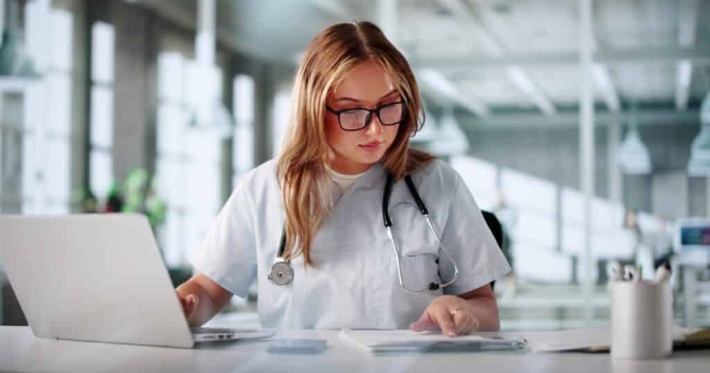 Medical billing manager auditing hospital codes on a laptop in a clinic.