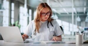 Medical billing manager auditing hospital codes on a laptop in a clinic.