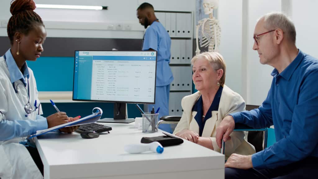African American healthcare provider speaking with an elderly woman with a disability during a checkup appointment, demonstrating an effective patient communication workflow for clinics.