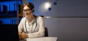 Attractive doctor wearing a headset using a laptop webcam for a video call