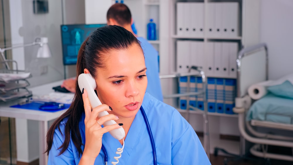 Doctor answering phone calls at hospital reception for patient callback and clinic communication