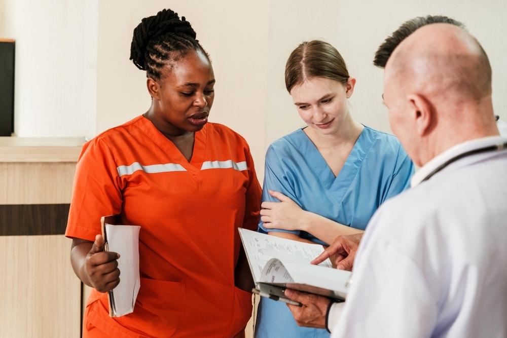 Doctors and nurses discussing patient charts during a hospital shift change to ensure effective healthcare communication