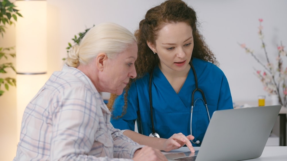 Female doctor helping an elderly woman schedule a medical appointment during a healthcare consultation