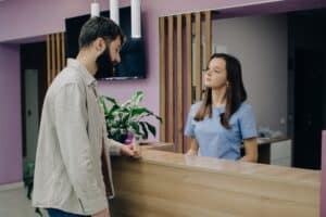 Male patient consulting with a medical receptionist about an appointment or healthcare services