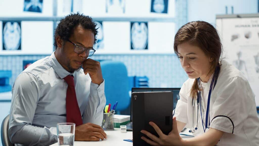 Patient communication support workflow for medical practices, doctor discussing test results and treatment findings with a patient during a clinic visit.