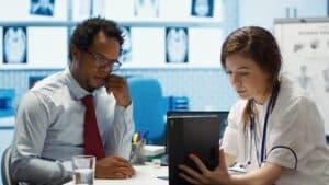Patient communication support workflow for medical practices, doctor discussing test results and treatment findings with a patient during a clinic visit.