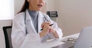 Young female medical professional attending a digital healthcare consultation on a laptop.