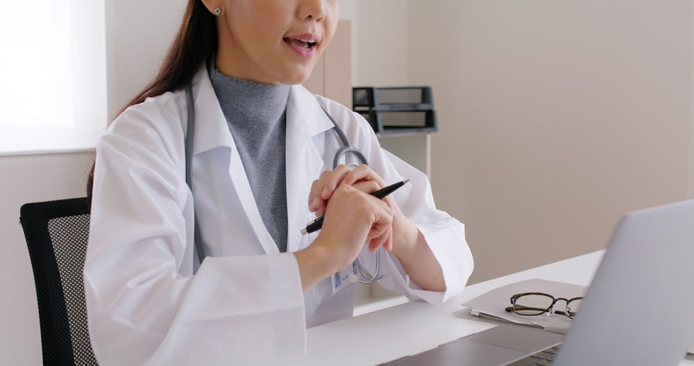 Young female medical professional attending a digital healthcare consultation on a laptop.
