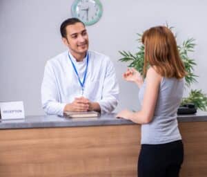 Young patient at hospital reception completing check-in for a medical appointment.