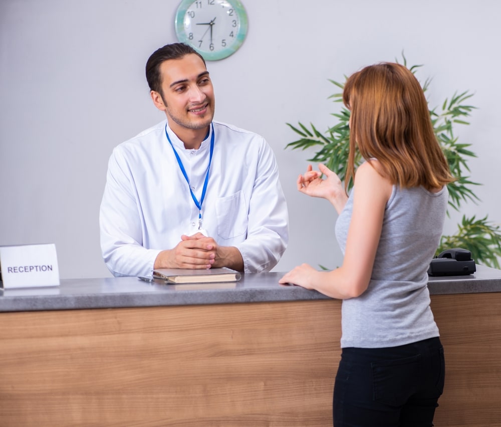 Young patient at hospital reception completing check-in for a medical appointment.