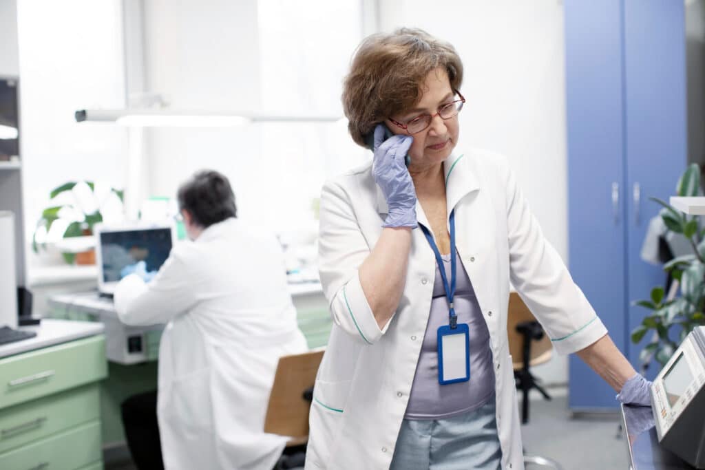 Doctor making a phone call in the office using patient callback scripts for missed medical appointments.