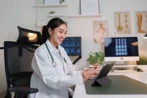 Doctor reviewing patient information on a tablet for after-hours voicemail triage for specialty practices.