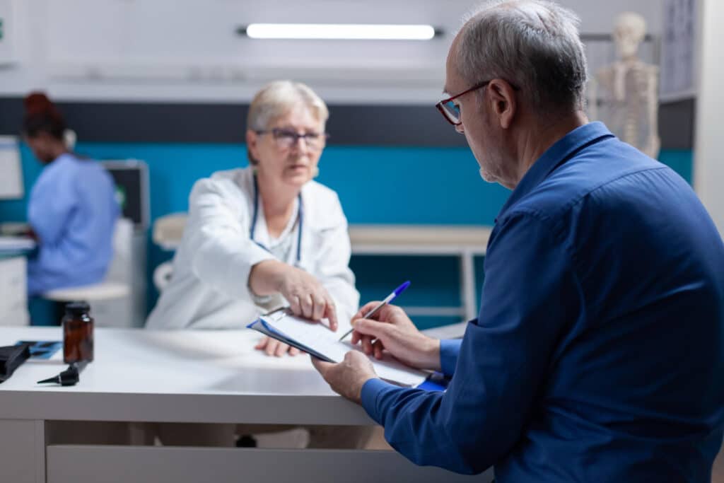 Senior patient signing appointment papers for doctor referral, specialist referral intake response standard.