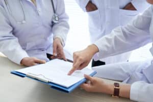 Doctors discussing medical documents as part of a medical practice review and response escalation protocol.
